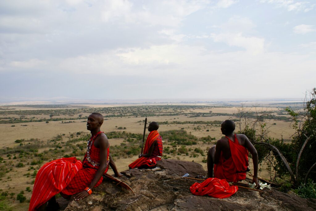 Maasai warriors sitted on a rock overlooking the plains of Maasai Mara